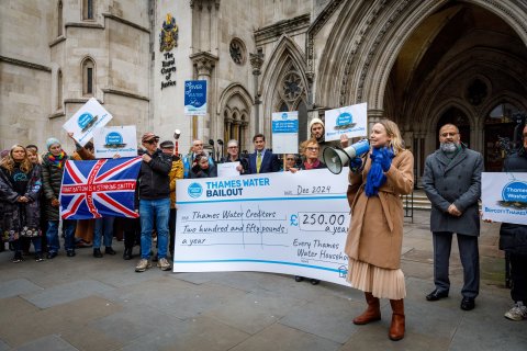 Block The Bailout! Protestors present a giant cheque showing the £250 a year the bailout deal would cost households each year. High Court back drop.