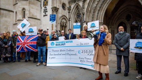 Block The Bailout! Protestors present a giant cheque showing the £250 a year the bailout deal would cost households each year. High Court back drop.